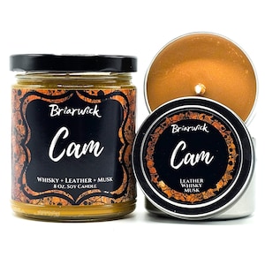 May include: A 8 ounce soy candle in a black and gold tin with a skull design. The candle is labeled "Briarwick Cam" and has a scent of whiskey, leather, and musk.