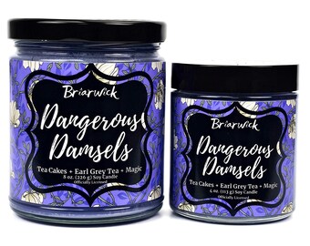 Puede incluir: Dos velas de soja en frascos de vidrio con tapas negras. Los frascos tienen un diseño floral morado y blanco con letras negras. El frasco más grande es de 8 onzas y el más pequeño es de 4 onzas. Ambas velas están etiquetadas como "Briarwick Dangerous Damsels Tea Cakes + Earl Grey Tea + Magic Officially Licensed."