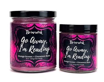May include: Two soy candles in glass jars with black lids. The larger candle is 8 ounces and the smaller candle is 4 ounces. Both candles have a pink floral design and the text "Go Away, I'm Reading" with the brand name "Briarwick". The scent is Orange Scones + Cinnamon Buns.