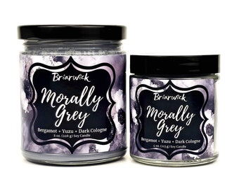 May include: Two glass candle jars with black lids. The larger jar is 8 ounces and the smaller jar is 4 ounces. Both jars have a black and white label with the text "Briarwick Morally Grey Bergamot + Yuzu + Dark Cologne" and a floral design.