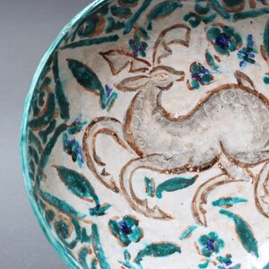 May include: A white ceramic bowl with a green and brown floral design and a stylized deer in the center.
