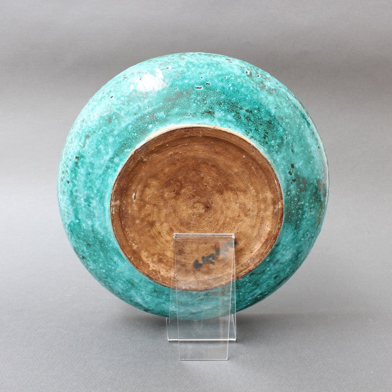 May include: A large, round ceramic plate with a turquoise glaze. The plate has a brown, unglazed base.