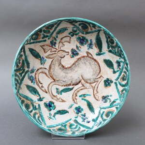 May include: A white ceramic bowl with a green and blue floral design and a stylized deer in the center.