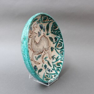 May include: A turquoise ceramic bowl with a white glaze and a painted design of a deer in a floral pattern.