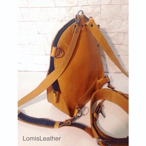 Puede incluir: Una mochila de cuero marr&oacute;n con correas ajustables y un bolsillo con cremallera. La mochila tiene un logotipo "LomisLeather" en la parte inferior.