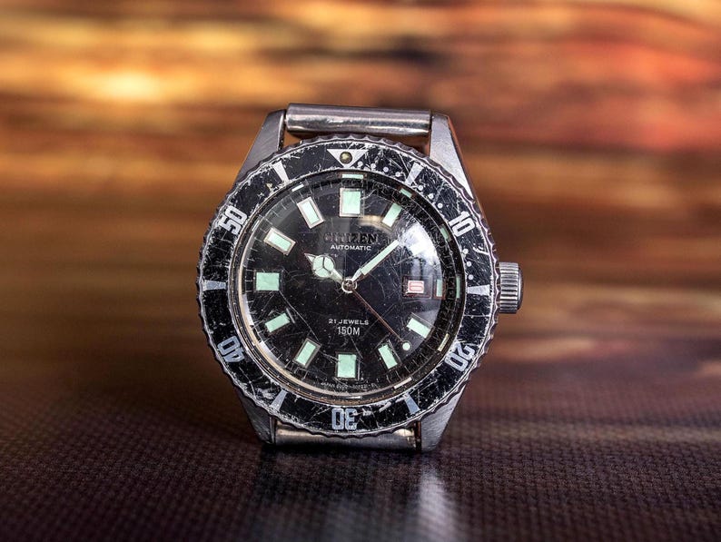Puede incluir: Un reloj de pulsera plateado vintage con esfera negra y marcadores luminosos. La esfera muestra la marca "CREENE" y "AUTOMATIC". El bisel tiene un aspecto desgastado y texturizado. Un reloj cl&aacute;sico.