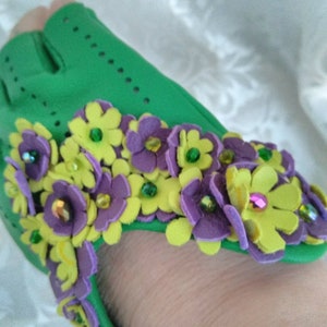 May include: Green fabric shoe with purple and yellow felt flowers with green and purple glitter accents.