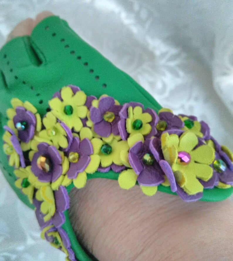 May include: Green fabric shoe with purple and yellow felt flowers with green and purple glitter accents.