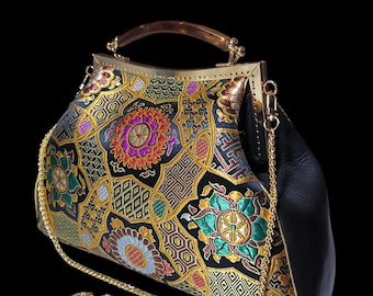May include: An ornate black handbag with a gold frame and handle. The bag features a colorful floral pattern with gold accents and a gold chain strap. The bag's side is black.