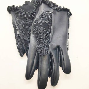 May include: A pair of black leather gloves with a lace design. The gloves have a ruffled edge and a floral pattern.