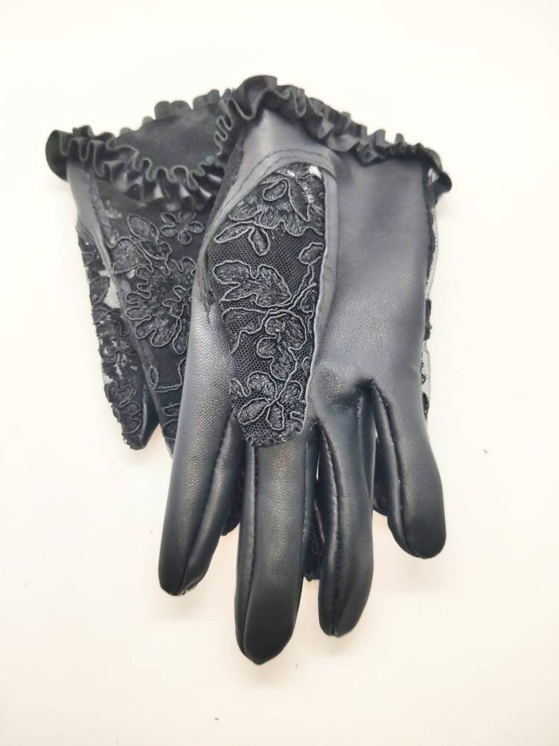 May include: A pair of black leather gloves with a lace design. The gloves have a ruffled edge and a floral pattern.