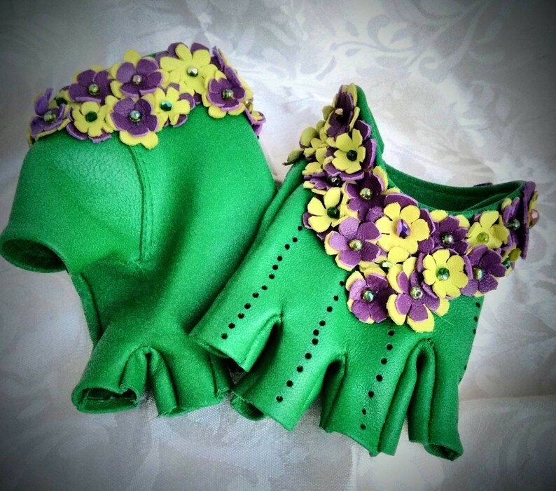 May include: A pair of green leather fingerless gloves with yellow and purple flower embellishments.