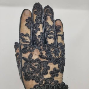 May include: Black lace gloves with a floral design. The gloves have a ruffled cuff.