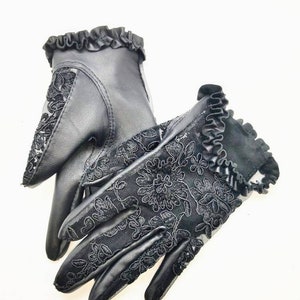 May include: A pair of black leather gloves with lace detailing and a ruffled trim.