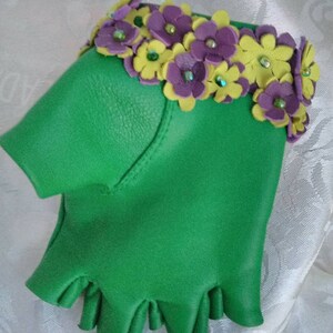 May include: Green leather fingerless gloves with a decorative trim of purple and yellow flowers with green rhinestones.