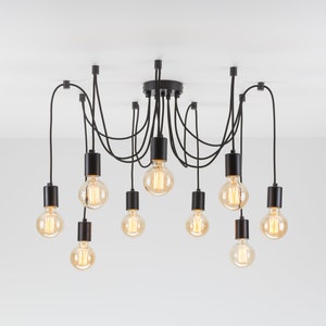May include: A black, multi-light pendant lamp with ten exposed Edison-style bulbs. The bulbs are warm-toned and encased in black cylindrical sockets. The fixture is mounted on a white ceiling.