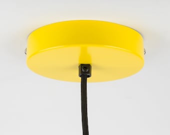 May include: Yellow ceiling canopy for a pendant light fixture. The canopy is round and has a black cord hanging from it.