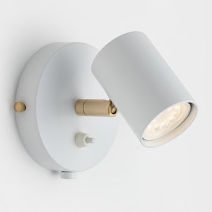 May include: White wall-mounted spotlight with a gold accent and a toggle switch. The light is adjustable and can be directed to highlight a specific area.