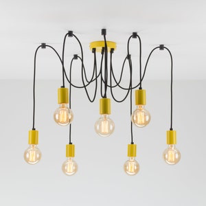 May include: A modern chandelier with eight Edison-style light bulbs. The fixture features black cords and yellow cylindrical bulb holders. The ceiling mount is also yellow. The light bulbs are round and emit a warm, inviting glow.