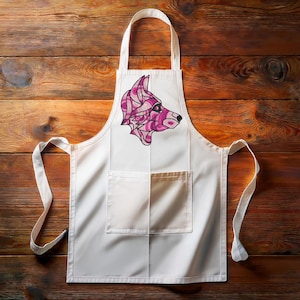 May include: White kitchen apron with a pink and black geometric wolf design. The apron has a large pocket in the front.