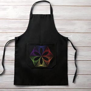 Puede incluir: Delantal negro con un diseño geométrico arcoíris bordado en el bolsillo delantero.