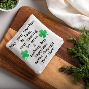 May include: White fabric pouch with green shamrock embroidery and the text "May your troubles be Less, your blessing be more & nothing but happiness comes through your door."
