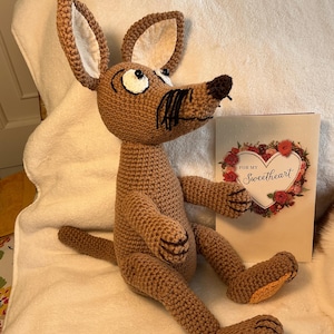 May include: A handmade brown crochet animal with large ears, a long snout, and black whiskers. The plush toy is sitting next to a greeting card with a heart-shaped floral design and the words "FOR MY Sweetheart".
