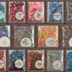 May include: A collection of glitter packets in various colors and shapes. The packets are labeled with names like "Forestland," "Carnival Love," and "Neon Butterfly." The glitter includes stars, butterflies, and other shapes, in colors like green, pink, and blue.