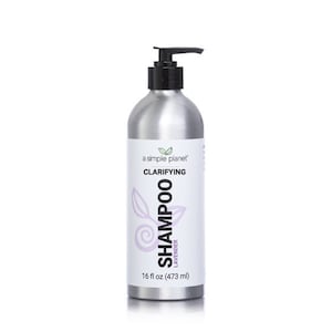 May include: A silver bottle of clarifying shampoo with a black pump top. The bottle is labeled "a simple planet" and "Clarifying Shampoo Lavender 16 fl oz (473 ml)".