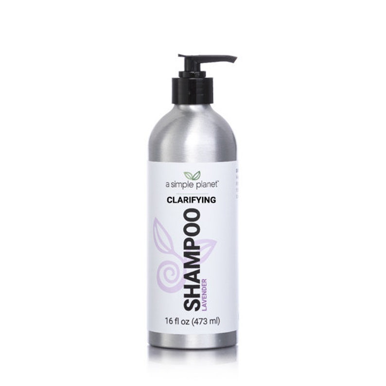 May include: A silver bottle of clarifying shampoo with a black pump top. The bottle is labeled "a simple planet" and "Clarifying Shampoo Lavender 16 fl oz (473 ml)".