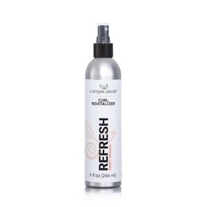 May include: A silver spray bottle with a black pump top and a white label that reads "a simple planet" and "CURL REVITALIZER". The label also features a green leaf logo and the text "REFRESH SWEET ORANGE" in a pink and orange color scheme. The bottle contains 9 fluid ounces (266 ml) of product.
