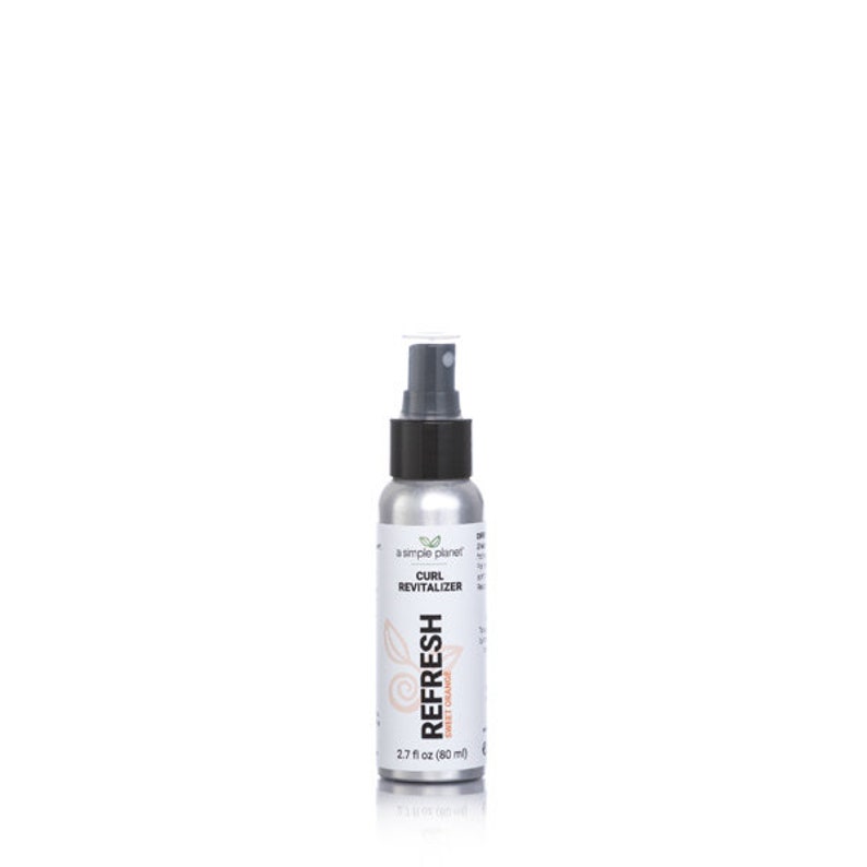 May include: A silver spray bottle with a black cap and a white label that says "a simple planet" and "CURL REVITALIZER" with the words "REFRESH" and "SWEET ORANGE" in a larger font. The bottle is 2.7 fl oz (80 ml).