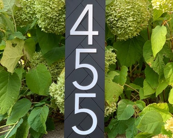 May include: Black house number sign with white numbers 455. The sign has a chevron pattern.