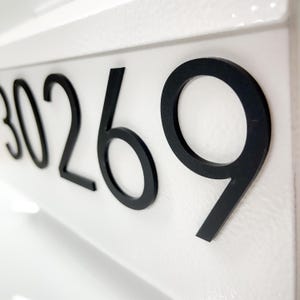 May include: A white rectangular house number plaque featuring the black raised digits 30269. The numbers are arranged horizontally with a clean sans-serif font, mounted on a smooth, solid white surface that provides a high-contrast background.