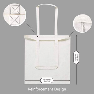 May include: A white canvas tote bag with reinforced stitching and handles. The bag measures 15 inches wide and 16 inches tall.
