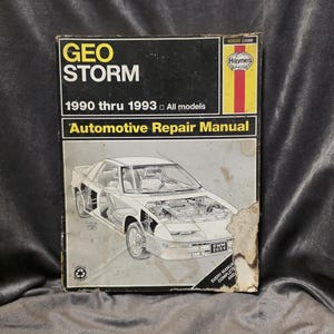 May include: A well-worn Haynes automotive repair manual for the Geo Storm, covering 1990 through 1993 models. The cover features a detailed illustration of the car and the Haynes logo. The manual is printed in black, white, yellow, and red.
