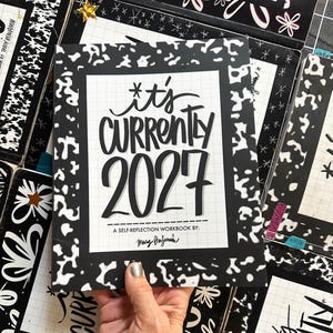 May include: A black and white workbook titled It's Currently 2027 A Self-Reflection Workbook by Tracy Benjamin. The cover features a grid pattern background with a black border and white abstract shapes. The text is in a bold, black, hand-lettered style.