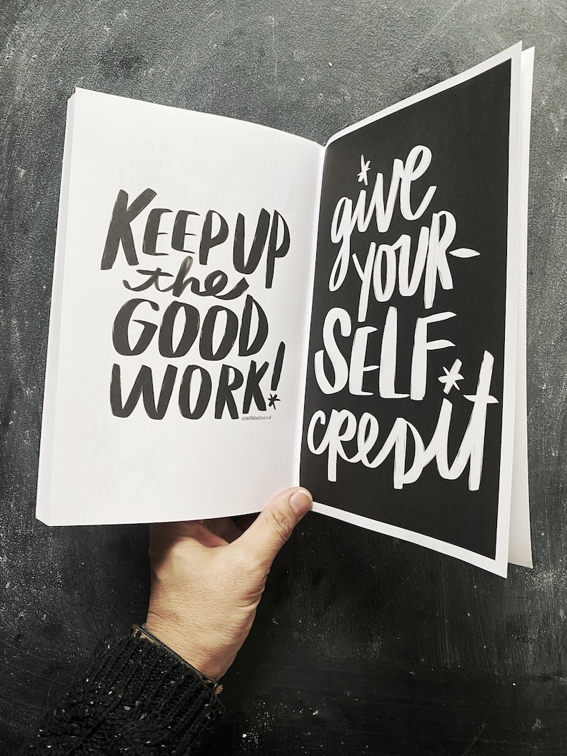 May include: Open book with black pages and white text. The left page says "Keep up the good work!" and the right page says "Give your self credit."