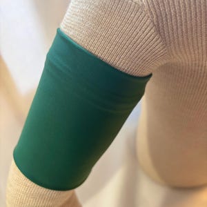 May include: A green fabric arm band for covering up a tattoo or other skin markings.