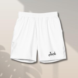 Puede incluir: Pantalones cortos deportivos blancos con cintura elástica y el nombre "Jack" impreso en escritura negra en la pierna. Los pantalones cortos están hechos de un material ligero y tienen un estilo casual.