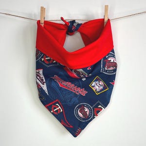 Op de afbeelding: Een blauwe en rode hondenbandana met het logo van het Minnesota Twins honkbalteam en de woorden "Minnesota Twins Baseball Club".