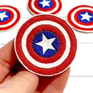 May include: Four red, white, and blue embroidered patches featuring Captain America's shield. The shield is a circle with a white star in the center, surrounded by concentric red and white circles.