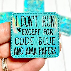Peut inclure: Un patch iridescent bleu clair avec une bordure cousue blanche. Le patch a du texte noir qui dit "Je ne cours pas *sauf pour le code bleu et les documents AMA".