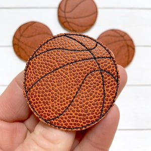 May include: Close-up of a brown leather basketball with black stitching. The basketball has a textured surface.
