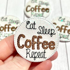 May include: Four white, round, glittery patches with black stitching. The patches have the text "Eat Sleep Coffee Repeat" in black and brown lettering.