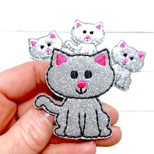 May include: Four silver glitter cat appliques with pink ears and noses. The cat appliques are ideal for adding a touch of whimsy to crafts and projects.