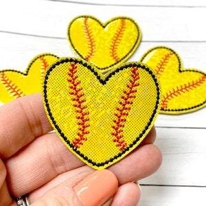 Peut inclure: Trois patchs de softball en forme de cœur jaunes avec des coutures rouges. Les patchs sont faits d'un matériau scintillant.