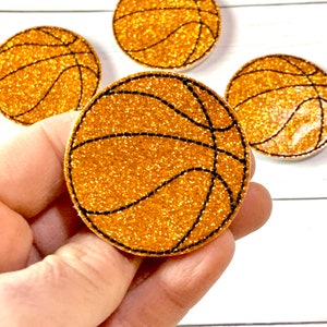 May include: Four gold glitter basketballs with black stitching. The basketballs are about 2 inches in diameter.