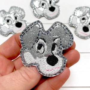 May include: Four silver glitter iron-on patches of a cartoon dog's face. The dog has black eyes, a black nose, and a pink mouth.