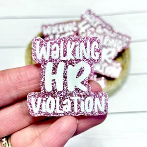 May include: A pink glittery badge with white lettering that reads Walking HR Violation. The badge has a scalloped, irregular shape and a textured, sparkling surface finish, with bold white text clearly displayed across the centre.